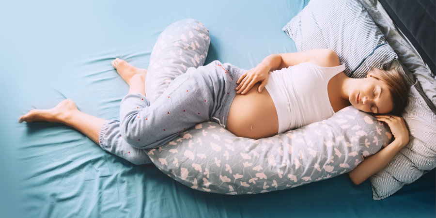 Pregnant woman using support pillow in bed