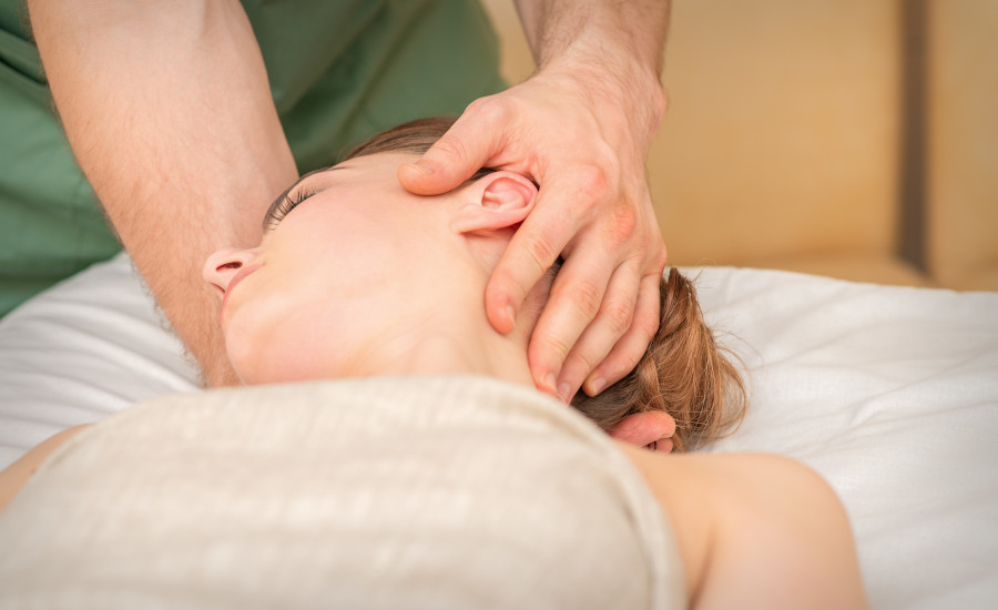 Osteopath doing massage on the female head in rehabilitation clinic