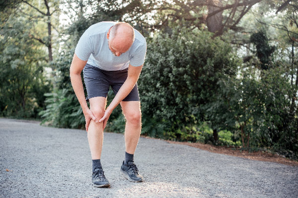 Man holding knee in pain whilst on a jog